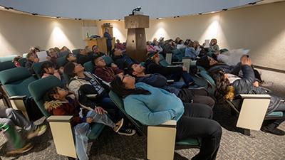 People sitting in the planetarium viewing an AstroFriday show.